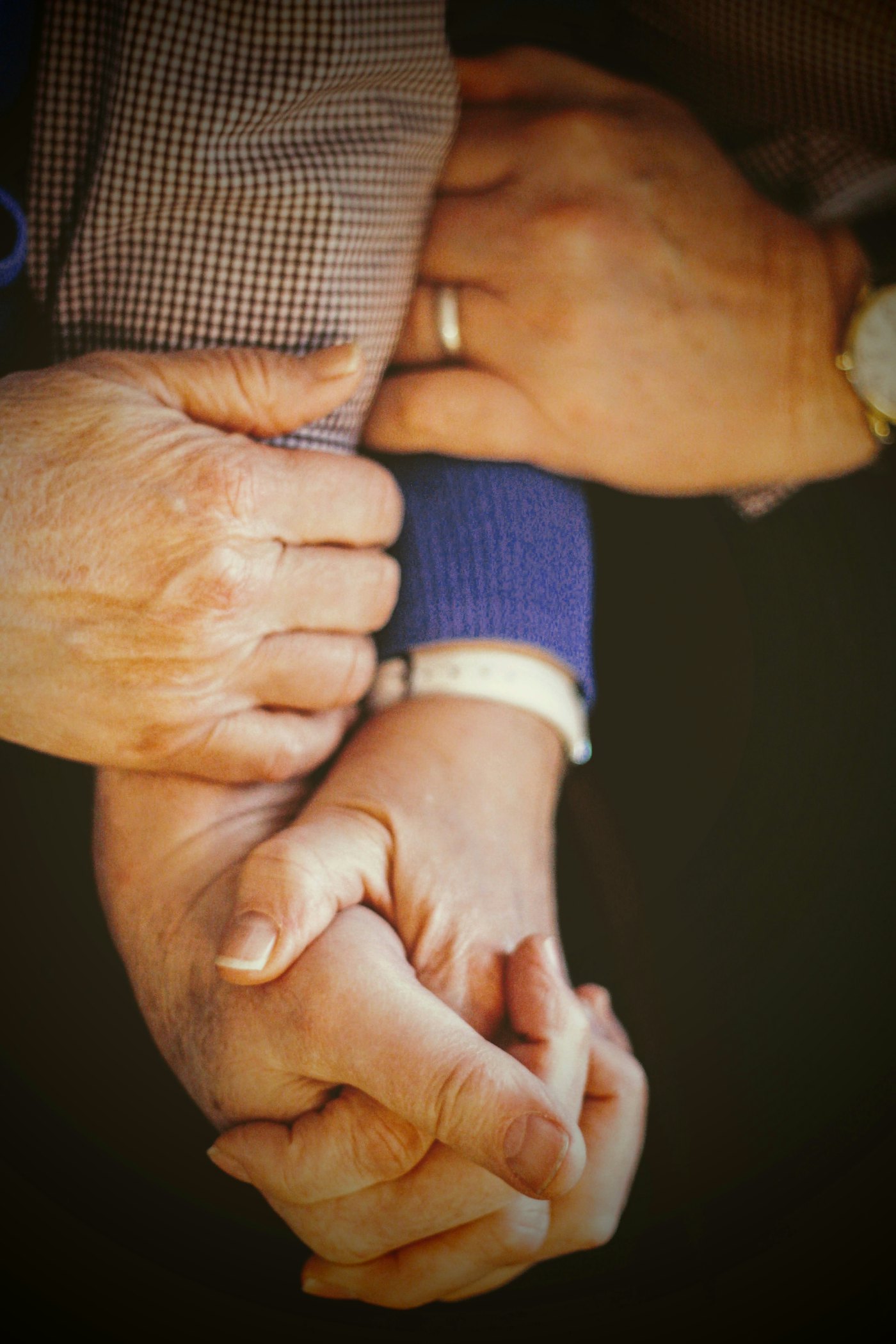 A carer gently holding the hand of an older person